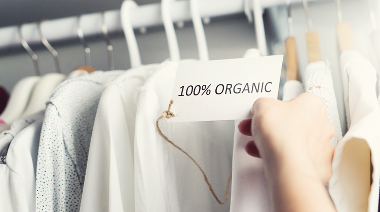 A row of light coloured blouses that have the tag '100% organic on them
